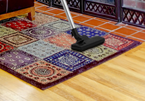 A rug with a vacuum on it in front of a fireplace.