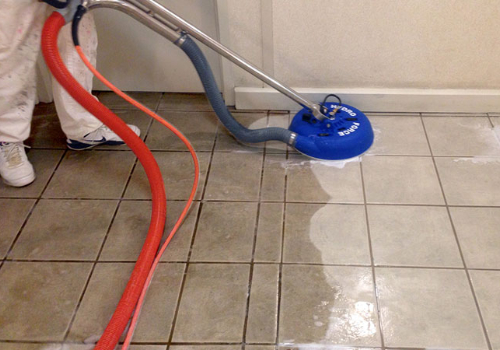 A tile floor being cleaned with a machine.